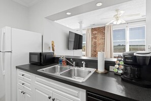 A modern kitchen with a double sink, a microwave, a coffee maker, and a television mounted on the wall. - Scot's Suite - Downtown Maryville Loft (Maryville)