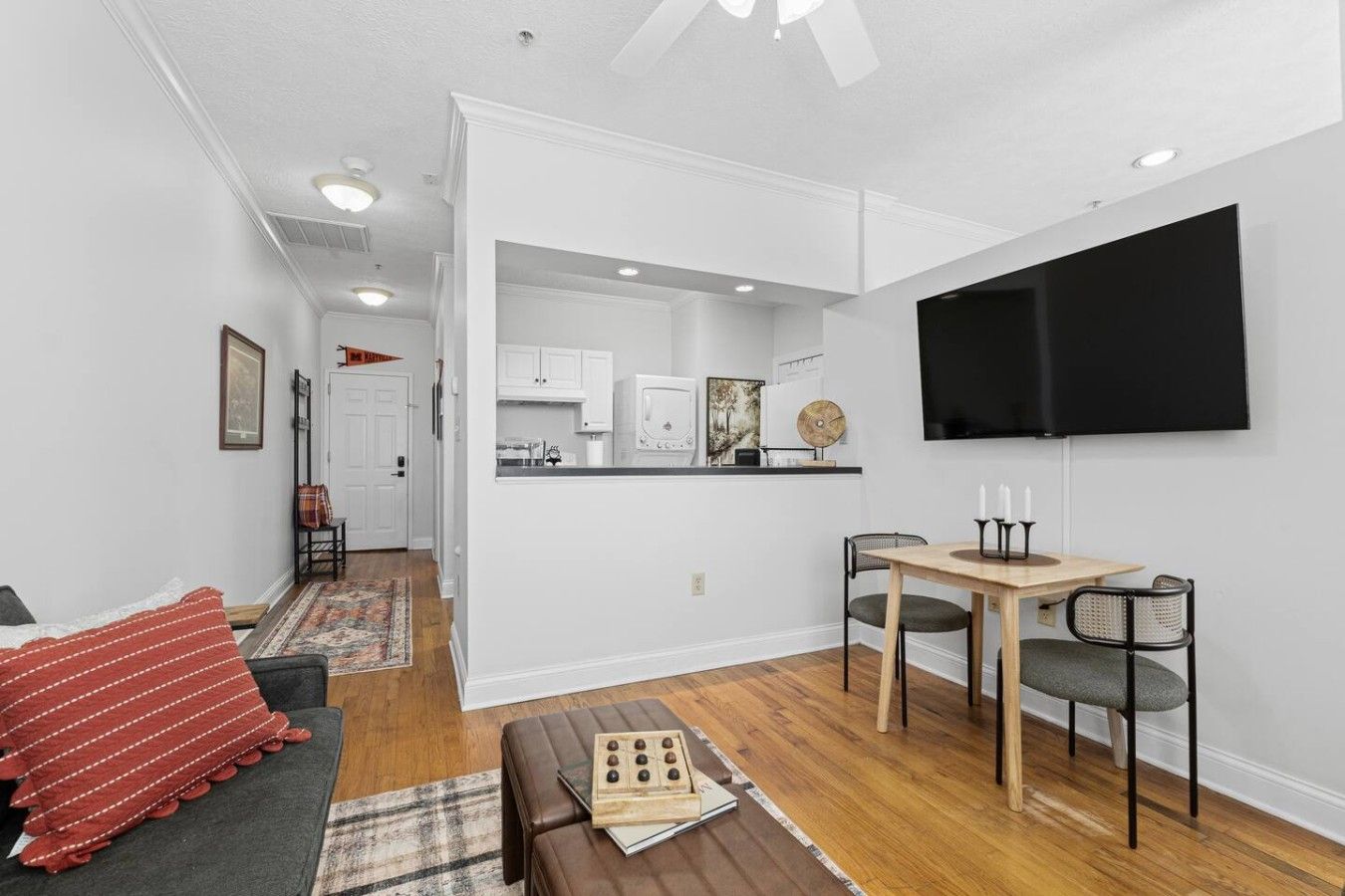 Un appartement moderne doté d’un coin repas, d’une kitchenette et d’un téléviseur à écran plat fixé au mur.