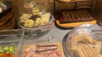En buffé med ett varierat utbud av mat, inklusive frukt, kött och smörgåsar.