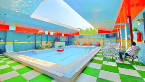 A swimming pool with a checkered floor, lounge chairs, and a covered seating area. - Hogis Luxury Suites and Hotel (Calabar)