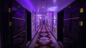 A hallway with a patterned carpet and doors on both sides. - Hogis Luxury Suites and Hotel (Calabar)