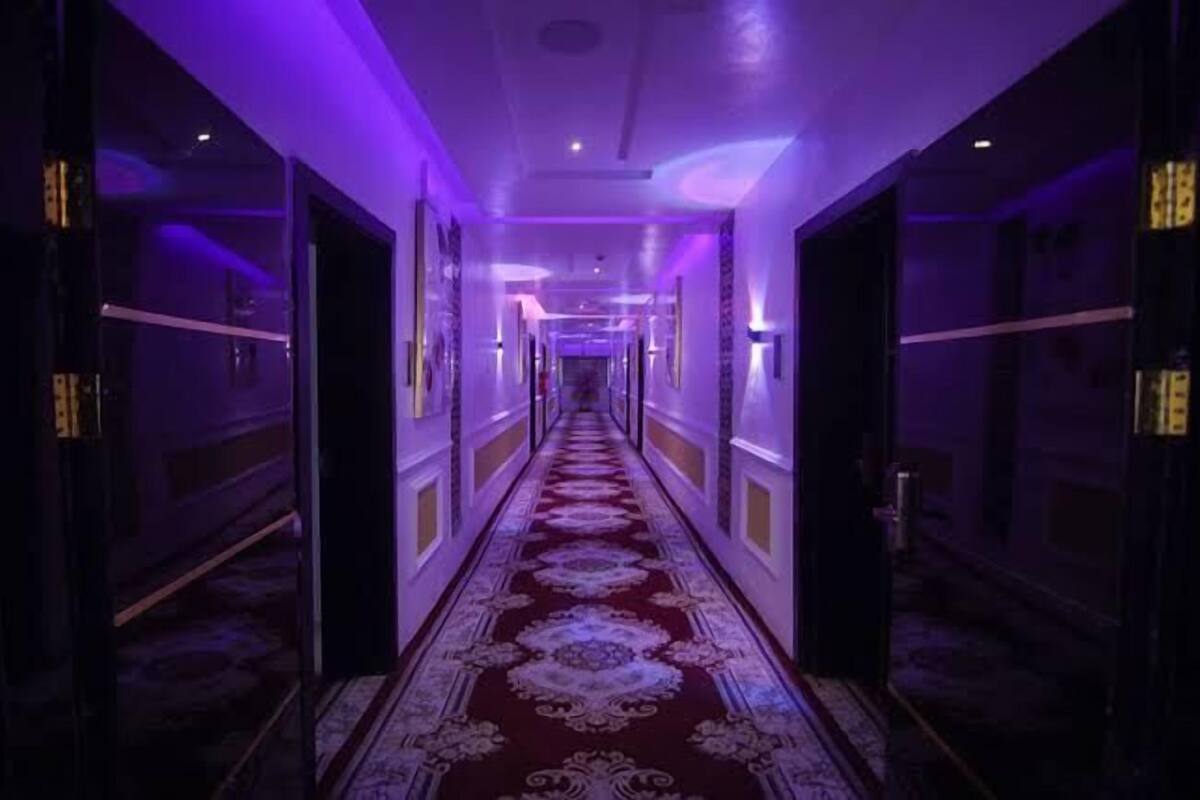 A hallway with a patterned carpet and doors on both sides.