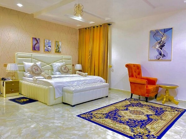Une chambre d’hôtel avec un grand lit, une chaise, une petite table et des œuvres d’art accrochées aux murs.