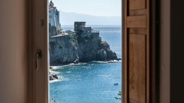 Una ventana con vista a un acantilado costero y al mar.