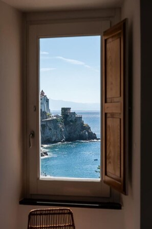 Una ventana con vista a un acantilado costero y al mar.