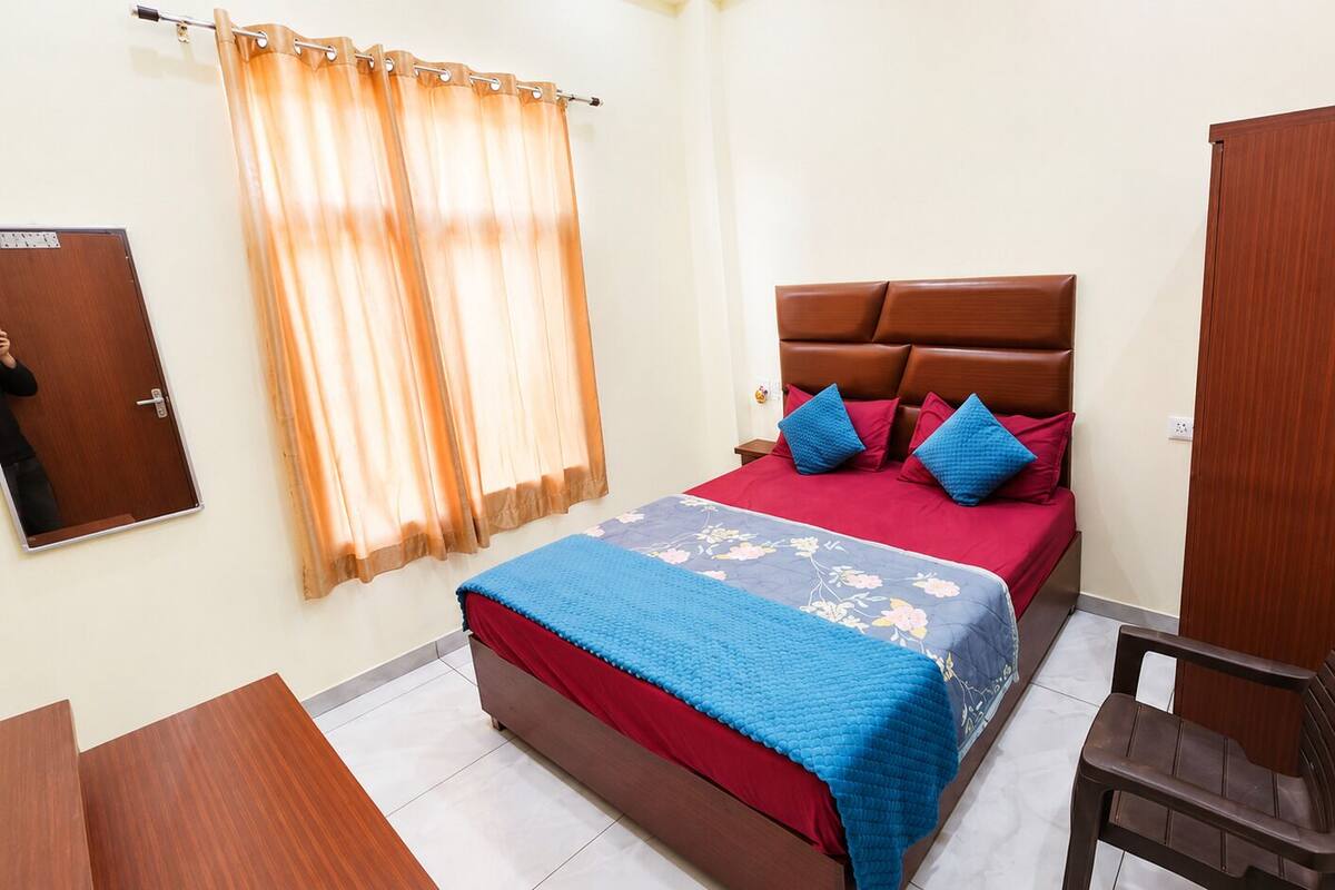 Un dormitorio con cama, una silla, un armario y un espejo.