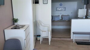 Ett kompakt bostadsutrymme med ett litet kök, en matplats och en liten sittgrupp.
