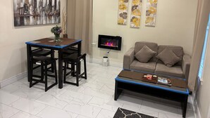 Un soggiorno con tavolo da pranzo, sedie, divano, tavolino, televisore e opere d'arte alle pareti.