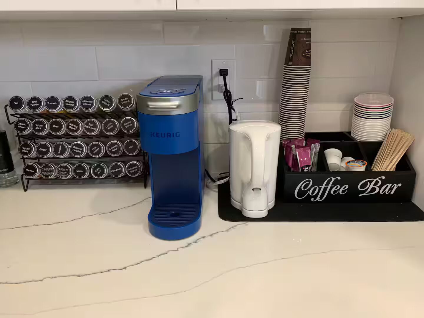 Eine Küchenarbeitsplatte mit einer Keurig-Kaffeemaschine, einer Kaffee-Bar und einem Gewürzregal.