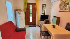 A compact living space with a red sofa, a dining table with chairs, a television, a refrigerator, and a cabinet. - Comfortable Crikvenica Stay With Private Parking (Crikvenica)