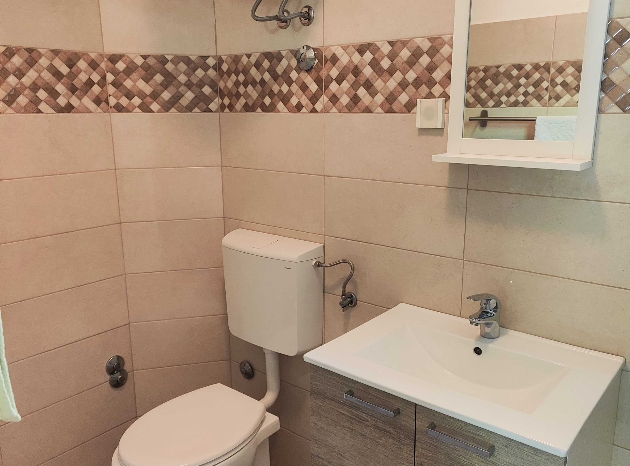 A bathroom with a toilet, sink, and a mirror above the sink.