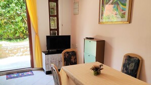 A room with a dining table, chairs, a television, a cabinet, and a window with curtains. - Comfortable Crikvenica Stay With Private Parking (Crikvenica)