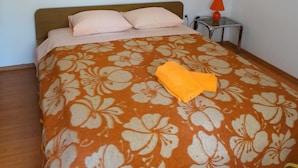 A bed with a floral-patterned bedspread, two pillows, and a folded towel on the bed. - Charming and Cozy Apartment Crikvenica (Crikvenica)