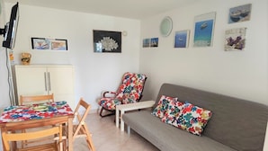 A cozy living room with a sofa, a floral-patterned chair, a wooden table, and a cabinet. - Charming and Cozy Apartment Crikvenica (Crikvenica)
