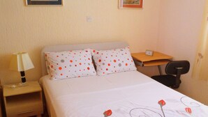 A hotel room with a bed, a nightstand with a lamp, a desk, and a chair. - Lush and Sunny Apartment With Balcony and Sea View (Crikvenica)