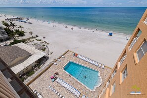 Blick auf einen Strand vom Hotel aus, mit Schwimmbecken und Strandliegen.