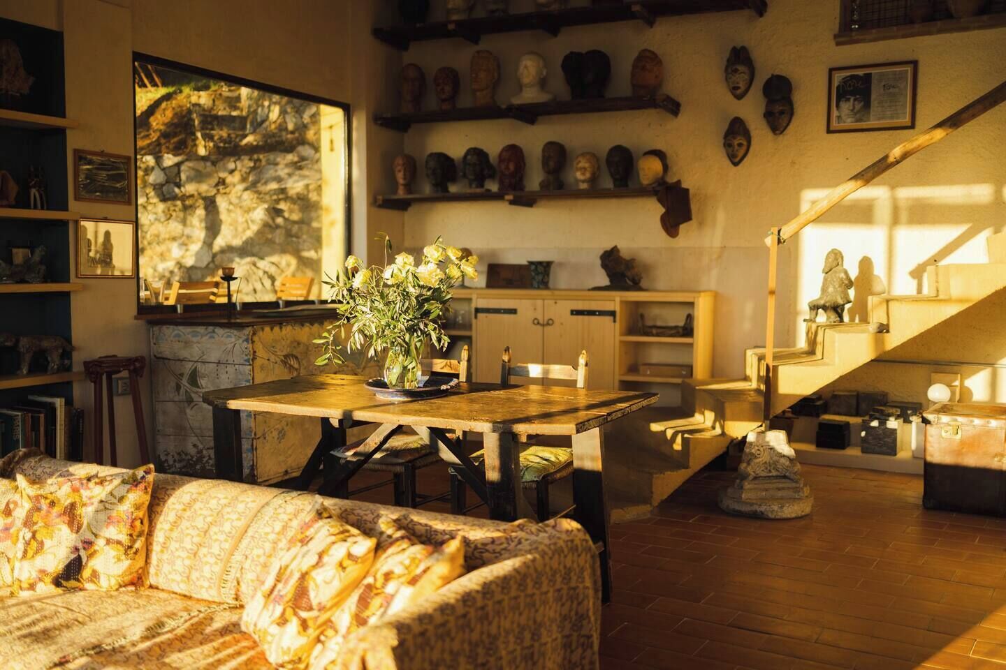 Uma sala de estar acolhedora com uma mesa de jantar de madeira, sofá estampado e um quadro na parede.