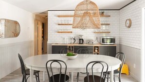 A modern kitchen with white subway tiles, a round dining table with chairs, and a hanging light fixture. - Bluebird Day - Lodgepole House: Spacious 3BR retreat in scenic Bend, OR, perfect for families. (Bend)