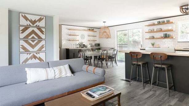A modern kitchen with white subway tiles, wooden shelves, and a dining area with a table and chairs. - Bluebird Day - Lodgepole House: Spacious 3BR retreat in scenic Bend, OR, perfect for families. (Bend)