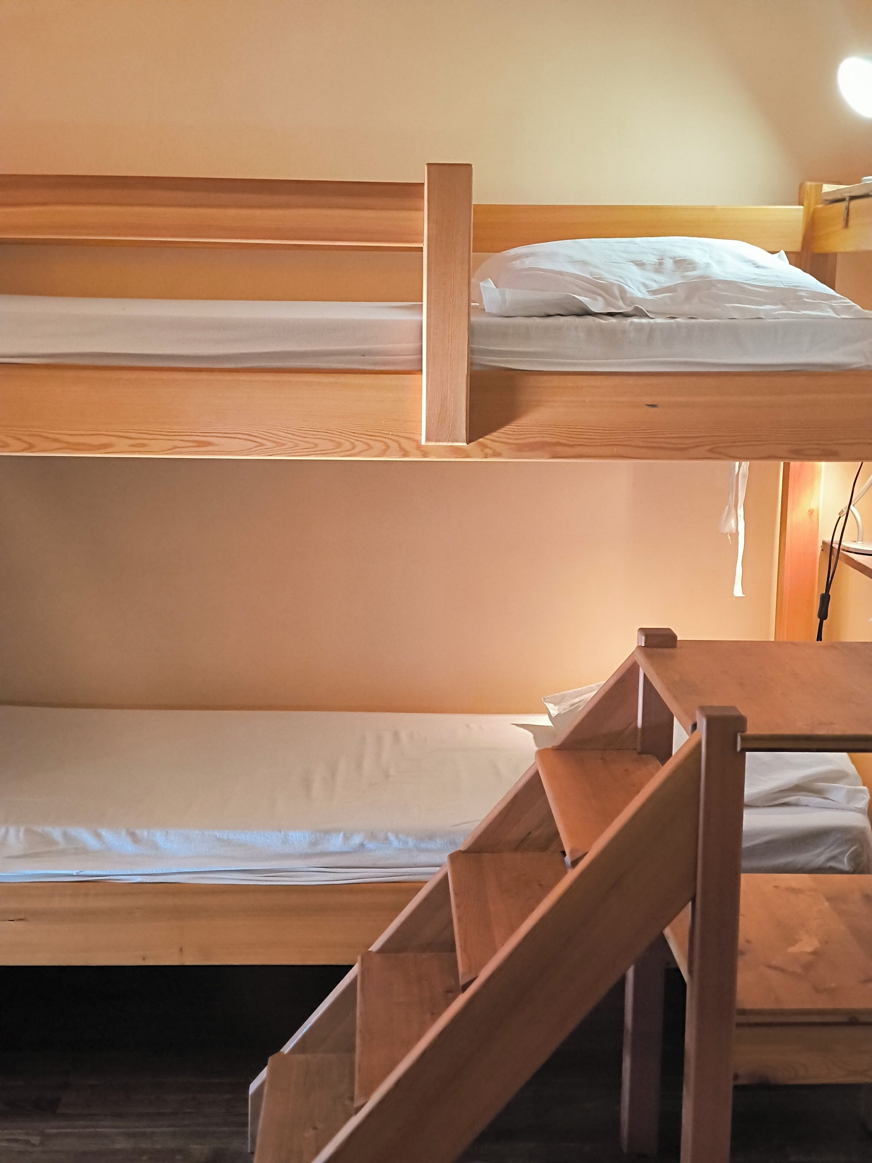 Een stapelbed met een houten frame en witte beddengoed.