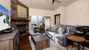 A living room with a fireplace, a large gray sofa, a wooden coffee table, and a ceiling fan. - Moose Mgmt at Black Rock 14151: Hot Tub, Views, Grill, King Beds (Park City)