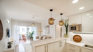 A modern kitchen with white cabinets, a central island, and pendant lighting. - Seaside Stay With Pool (Estepona)