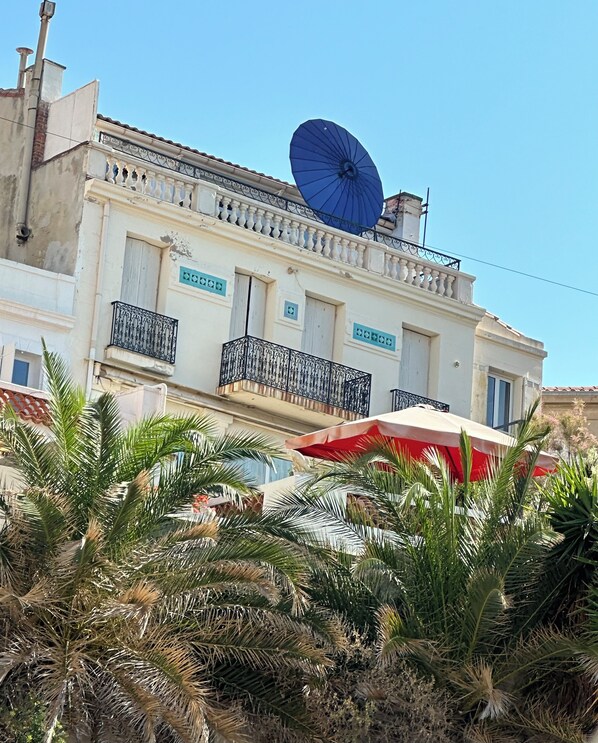 A building with balconies, a satellite dish, and palm trees.