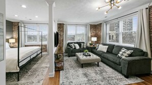 Ein modernes Wohnzimmer mit einem Bett, einem grauen Sofa und einem Couchtisch.