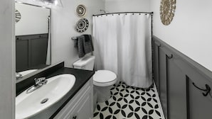 Baño con lavamanos, inodoro y cortina de ducha.
