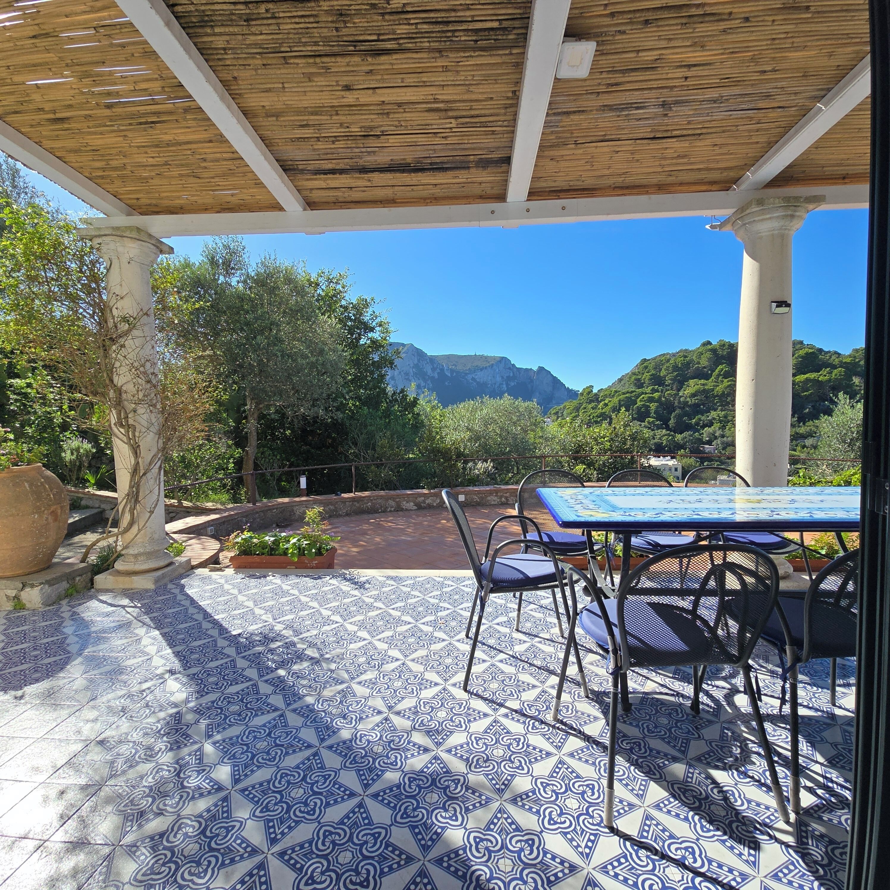 Eine Außenpatio mit gemustertem Boden, einem Tisch mit Stühlen und Blick auf Berge.