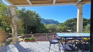 An outdoor patio with patterned flooring, a table with chairs, and a view of mountains.