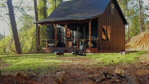 A rustic cabin with a covered porch, surrounded by trees and a dirt path. - Hidden Springs Cottage, Rome, GA, King Loft Bedroom, Private Lake Access (Rome)
