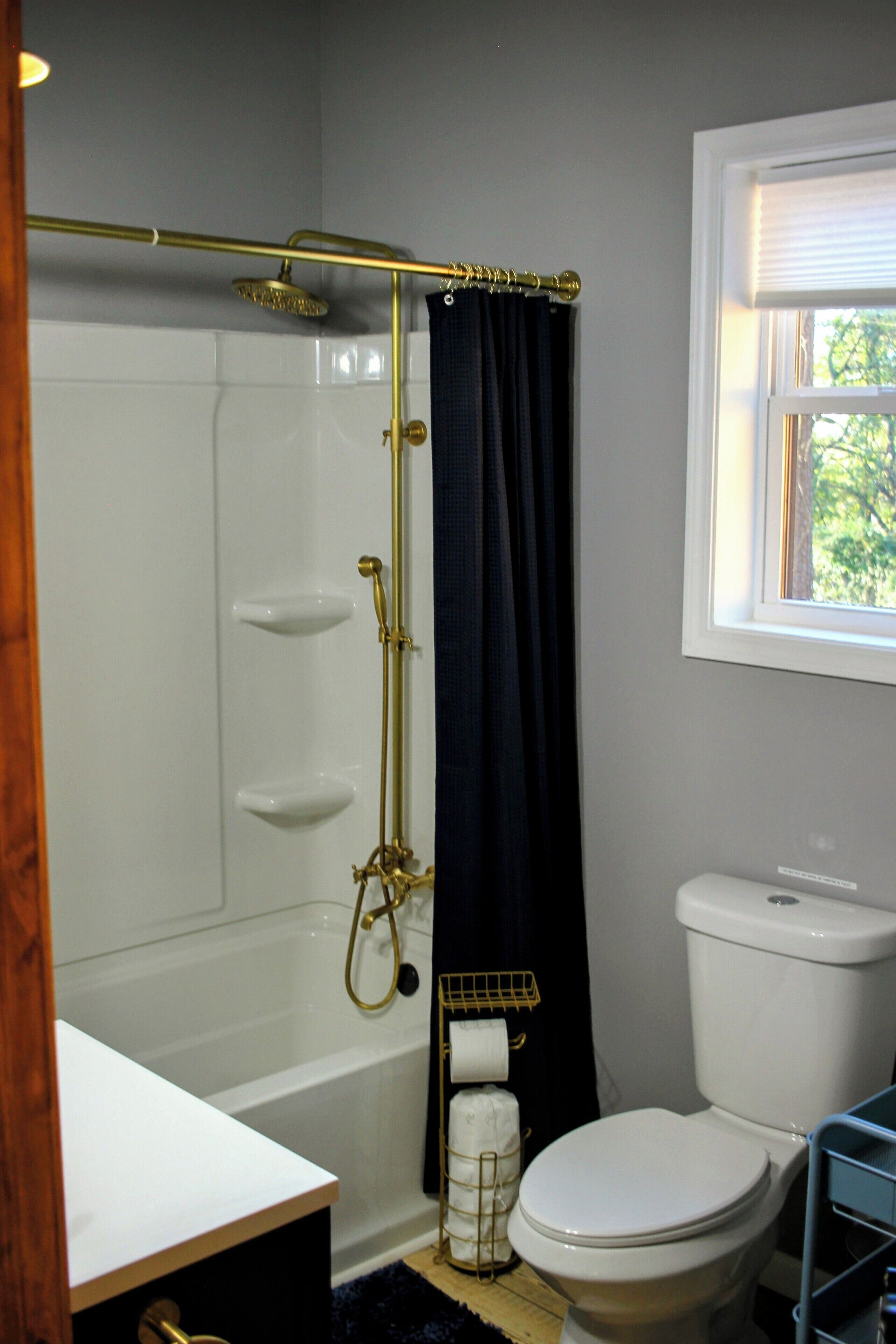 A bathroom with a bathtub, toilet, and a window.