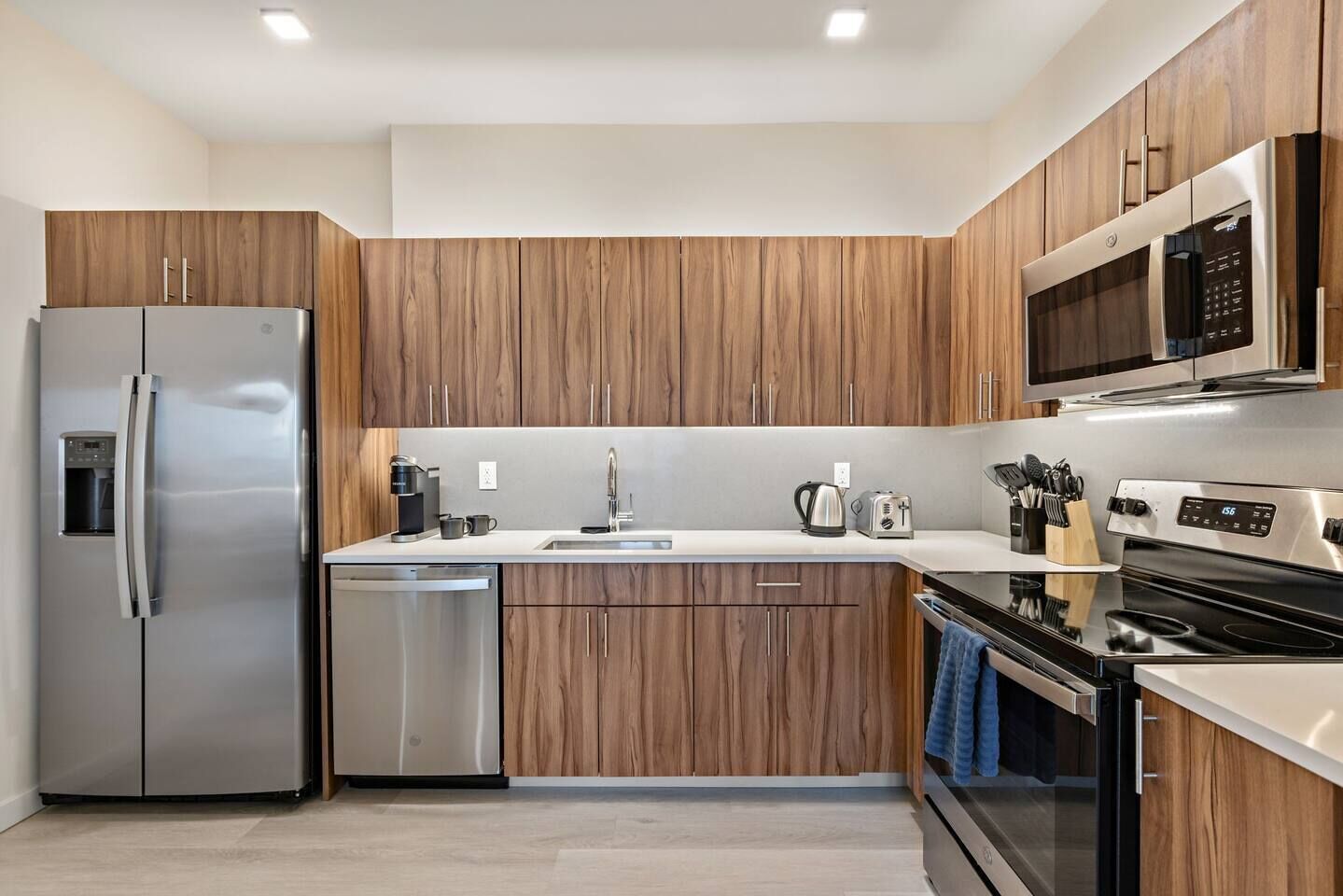 Una cocina moderna con armarios de madera, electrodomésticos de acero inoxidable y un microondas integrado.