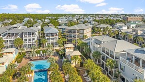 A resort with multiple-story buildings, a swimming pool, and palm trees.