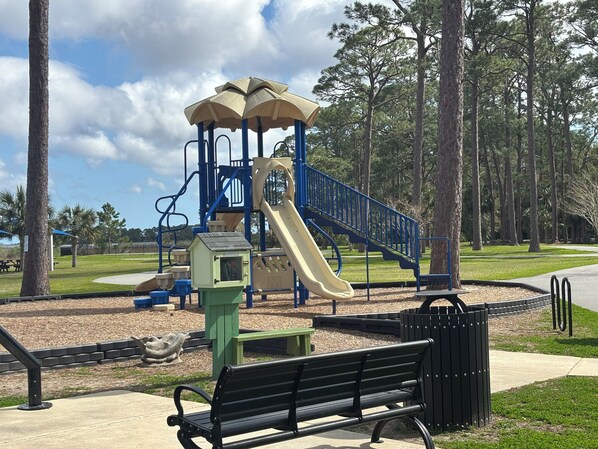 A playground with a slide, climbing structures, and a bench.