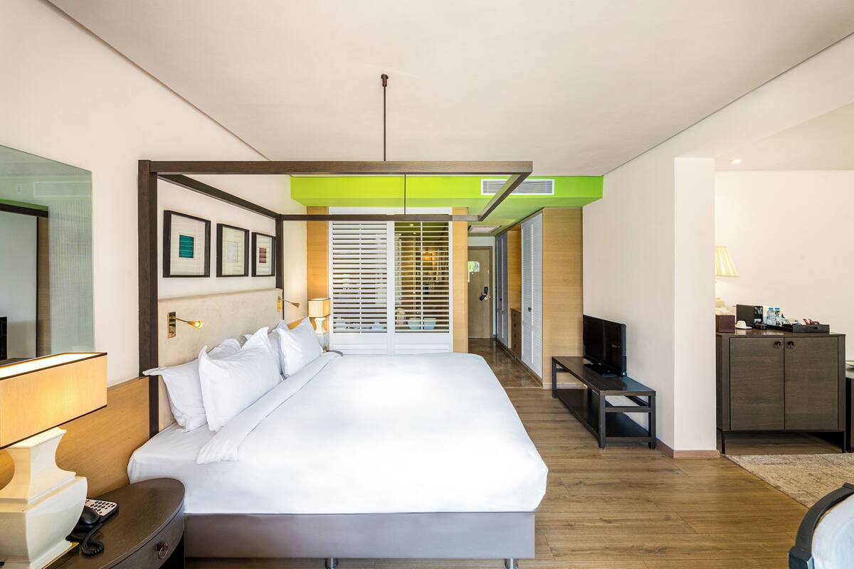 Une chambre d’hôtel moderne, dotée d’un grand lit, de tables de chevet, d’un téléviseur et d’une armoire.