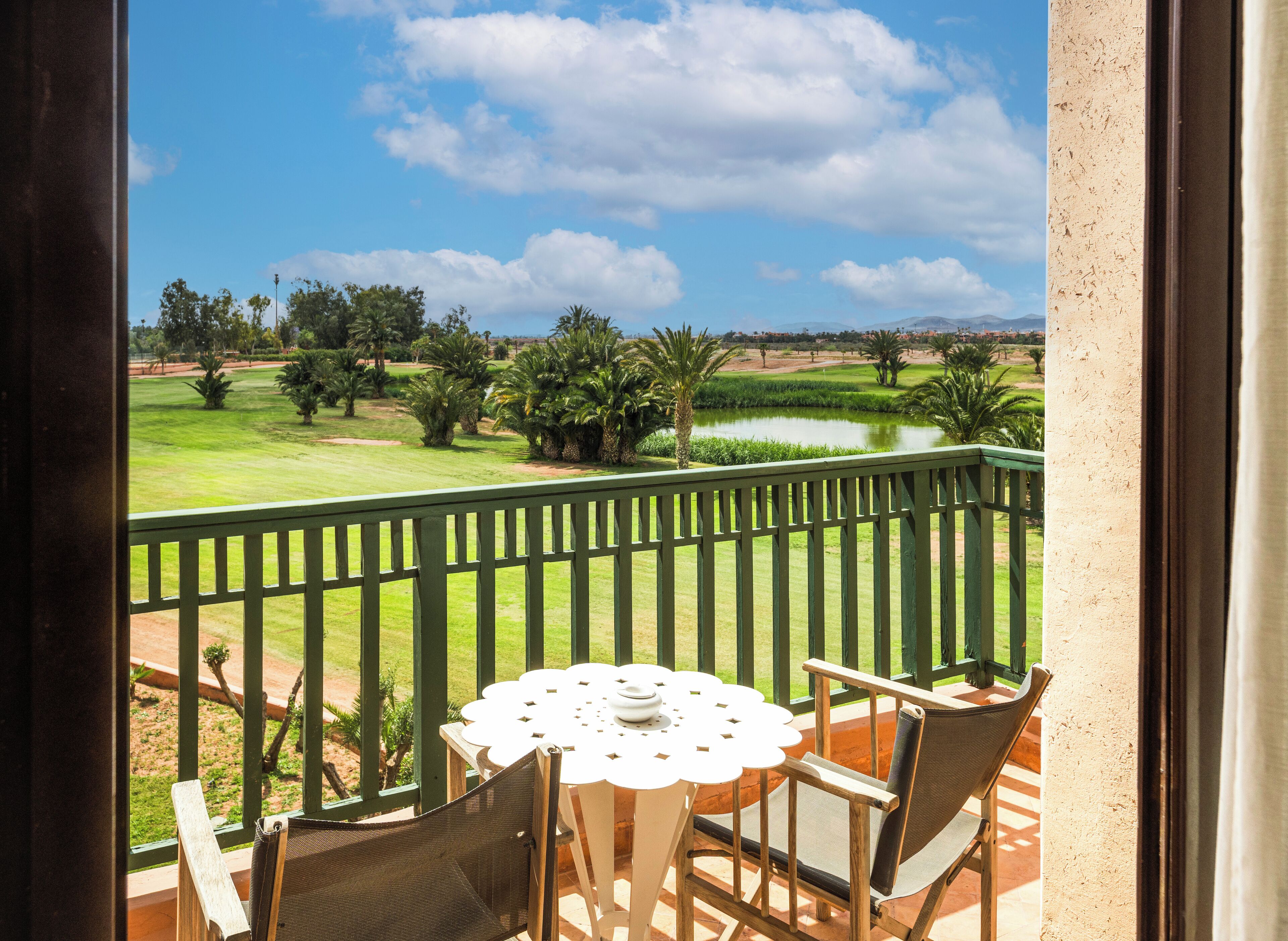 Un balcón con vista a un campo de golf, una mesa con sillas y una piscina pequeña.