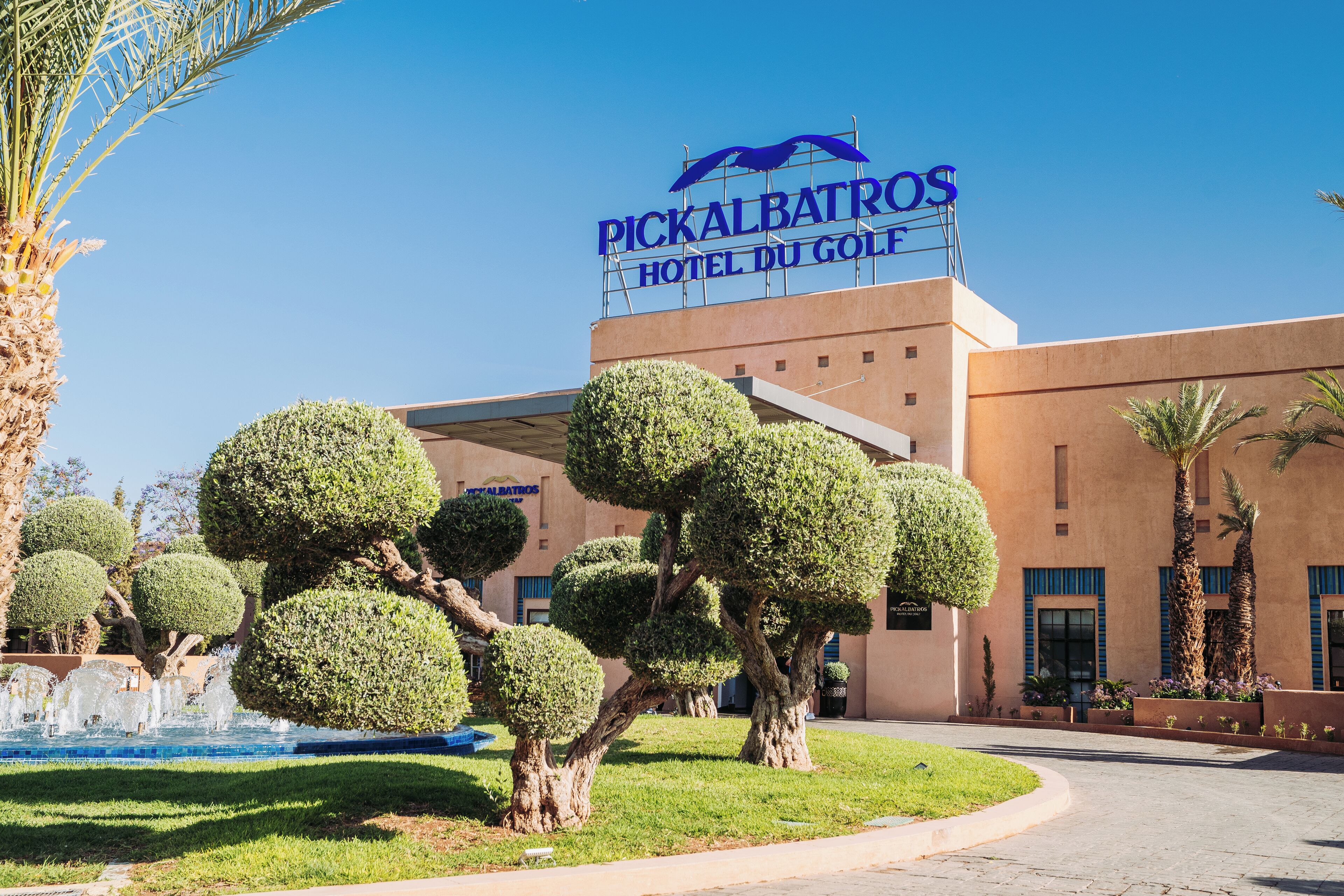 Hotel Pickalbatros Du Golf, con cielo despejado, césped bien cuidado y un letrero.
