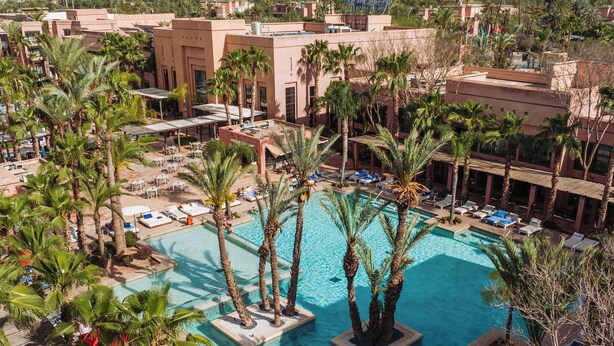 A resort with a central swimming pool surrounded by palm trees, lounge chairs, and a poolside deck. - Pickalbatros Hôtel Du Golf - Adults Friendly 16 Years Plus- All-Inclusive (Marrakech)