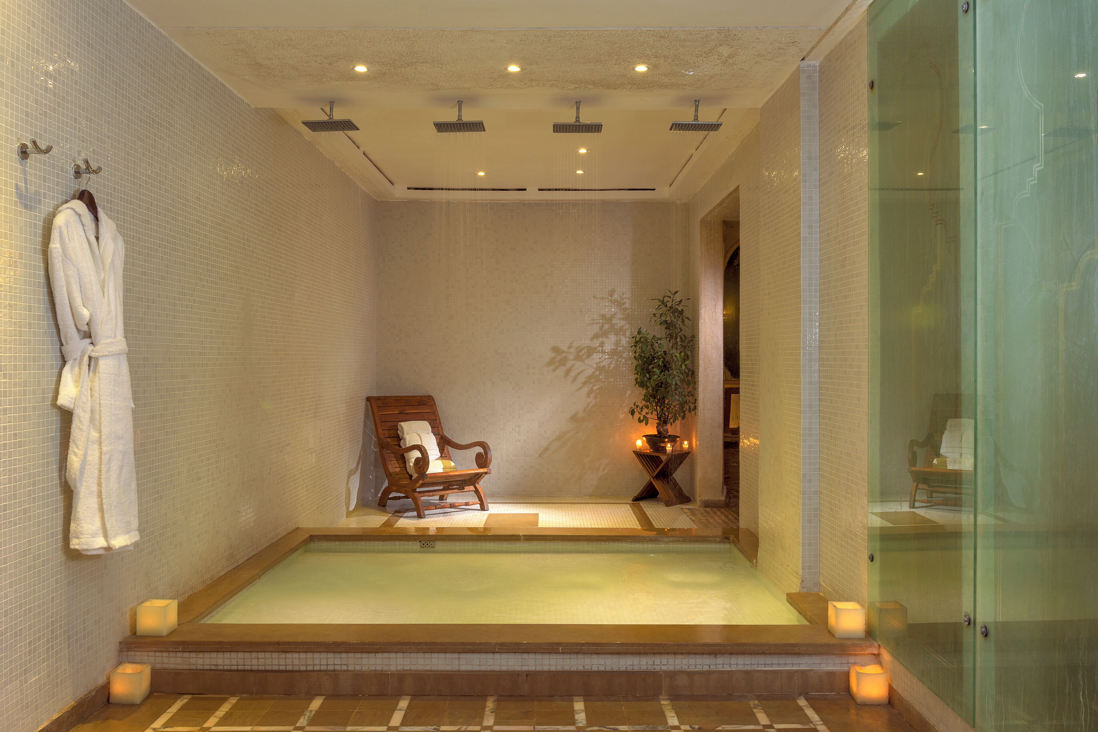 A spa room with a large bathtub, a wooden chair, and a potted plant.