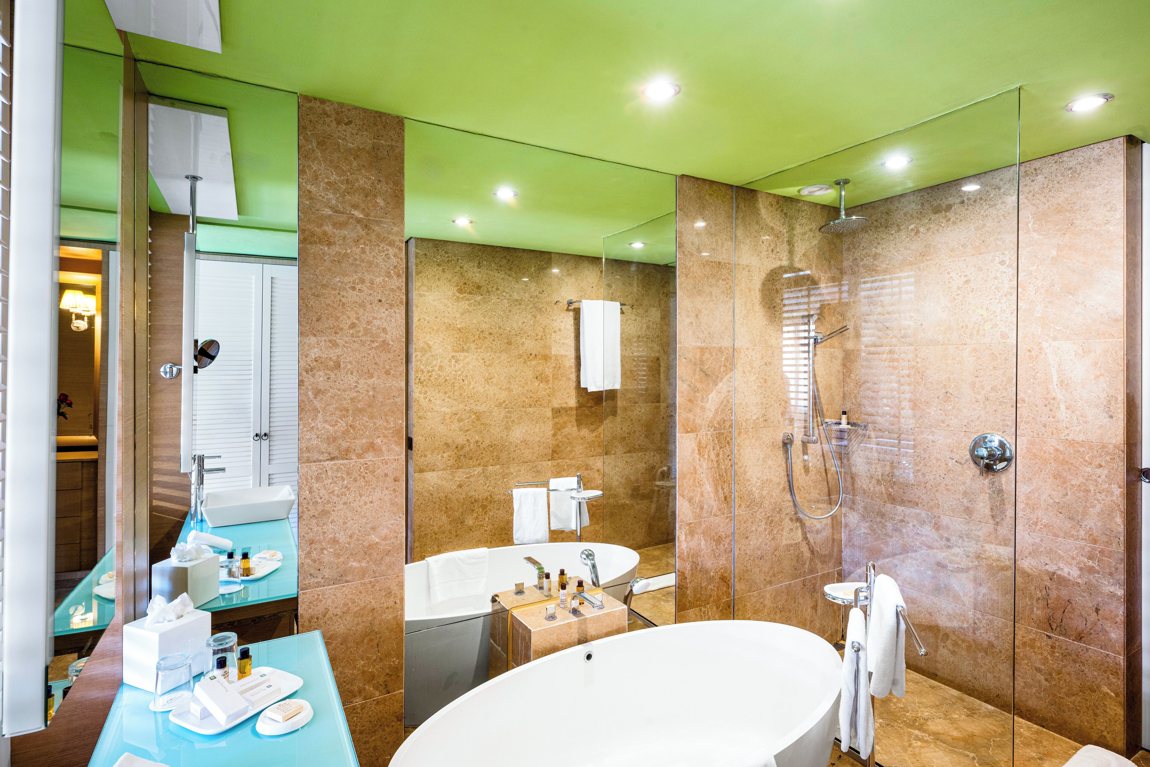 A modern bathroom with a large oval bathtub, a glass-enclosed shower, and a vanity with a mirror and sink.