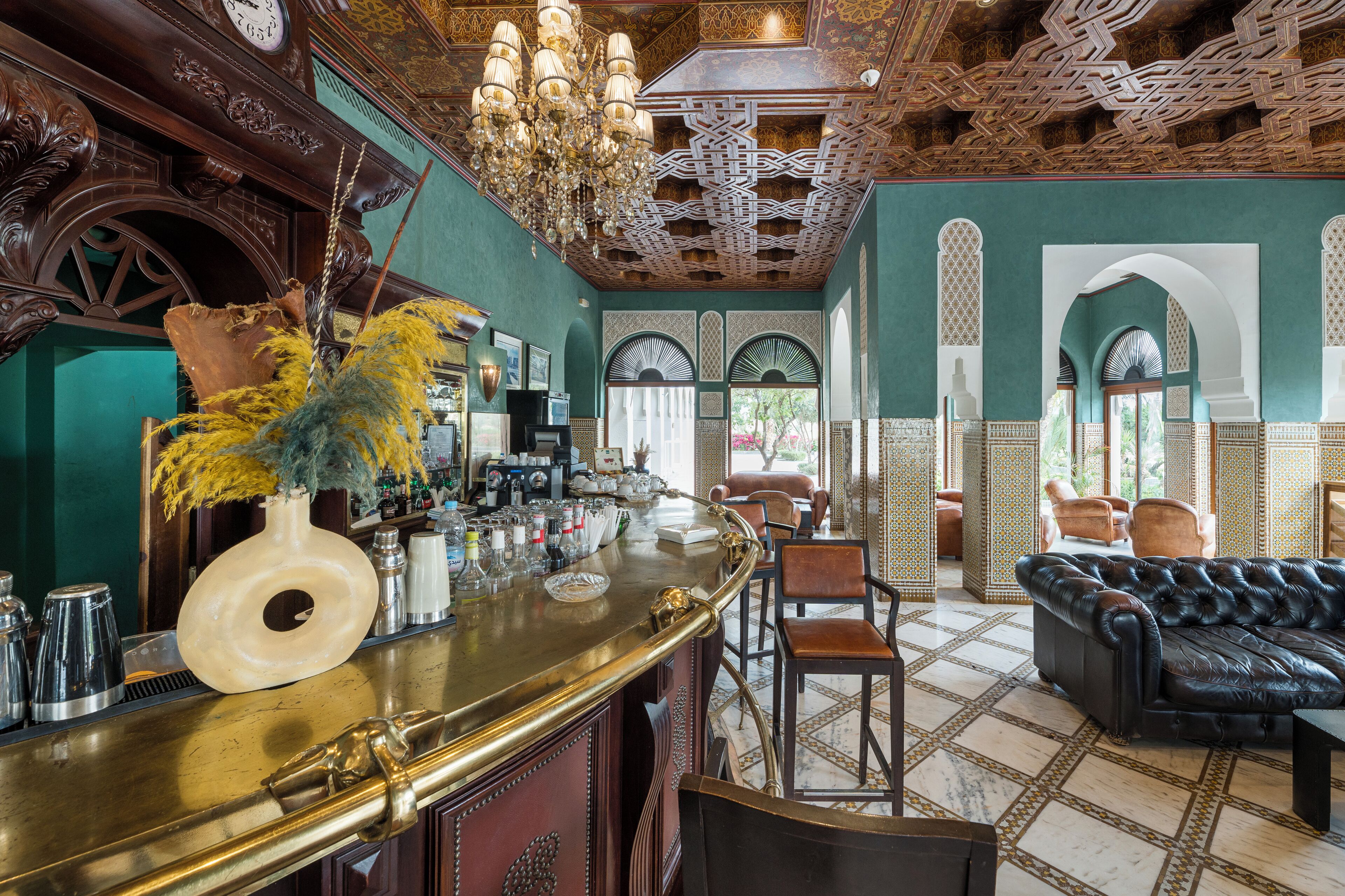 A bar area with a bar counter, chairs, and a sofa.
