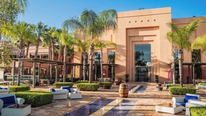 A hotel courtyard with outdoor seating, palm trees, and a modern building facade. - Pickalbatros Hôtel Du Golf - Adults Friendly 16 Years Plus- All-Inclusive (Marrakech)