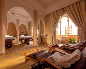 Relax in this serene spa room with a bathtub, massage table, and arched window.