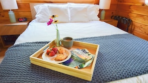 A neatly made bed with white linens, a tray with breakfast items, a vase with flowers, and a clock on the bedside table. - Cabin, Hot Tub, Fire Pit, 4 miles to Downtown AVL (Asheville)