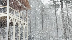 A wooden cabin with a balcony, surrounded by tall pine trees in a snowy landscape. - Cabin, Hot Tub, Fire Pit, 4 miles to Downtown AVL (Asheville)