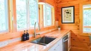 A wooden cabin interior with a kitchen featuring a sink, countertop, and cabinets. - Cabin, Hot Tub, Fire Pit, 4 miles to Downtown AVL (Asheville)