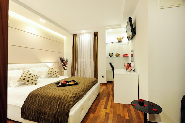 A hotel room with a bed, a small desk, a TV mounted on the wall, and a wooden floor. - Main street studio and rooms (Zadar)