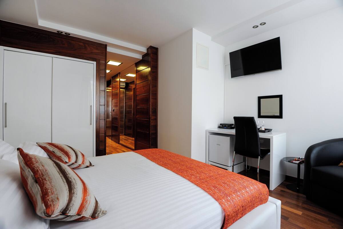 Una habitación de hotel con cama, escritorio, silla, televisor y armario.